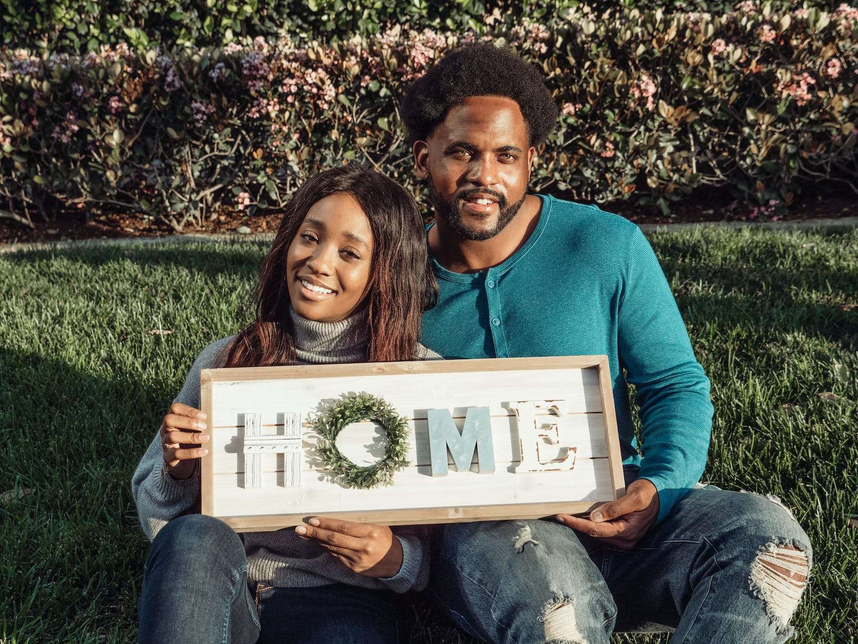 man in blue sweater sitting beside woman in gray sweater holding brown wooden home decoration