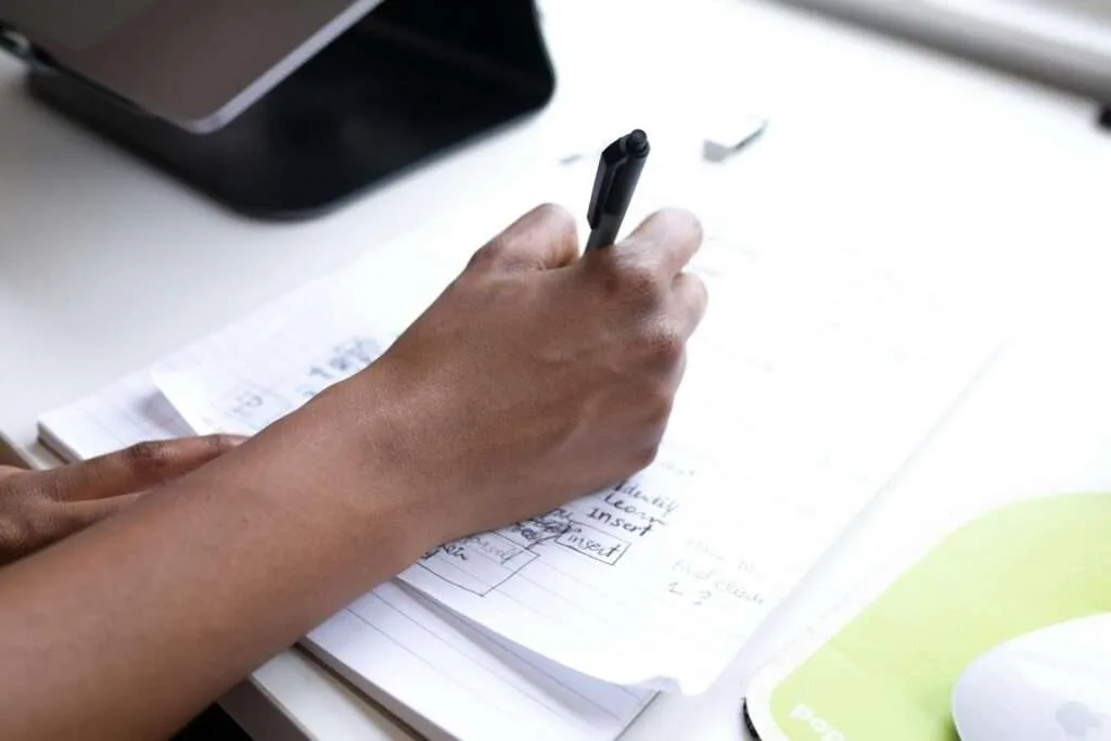 crop faceless employee writing on paper during workday