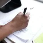 crop faceless employee writing on paper during workday