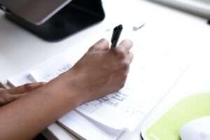 crop faceless employee writing on paper during workday